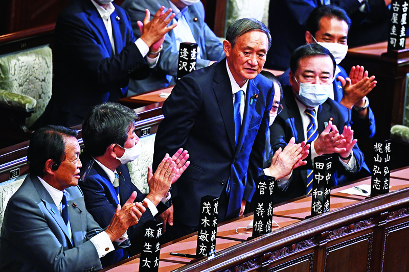 Newly elected leader of Japan's Liberal Democratic Party (LDP) Yoshihide Suga (C) is applauded by Deputy Prime Minister and Finance Minister Taro Aso (L), Foreign Minister Toshimitsu Motegi (2nd L) and other officials after he was elected as Japan's prime minister by the Lower House of parliament in Tokyo on September 16, 2020. - Japan's parliament votes on September 16 for the country's next prime minister, with powerful cabinet secretary Yoshihide Suga all but assured the top job, as Shinzo Abe ends his record-breaking tenure. (Photo by CHARLY TRIBALLEAU / AFP)