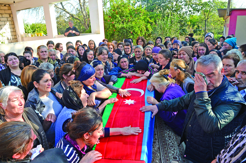 People gather around the coffin of an Azeri serviceman who is said was killed in fighting with Armenian separatists over the breakaway Nagorny Karabakh region, during a funeral ceremony in a settlement in Azerbaijan's Beylagan district on September 30, 2020. (Photo by TOFIK BABAYEV / AFP)