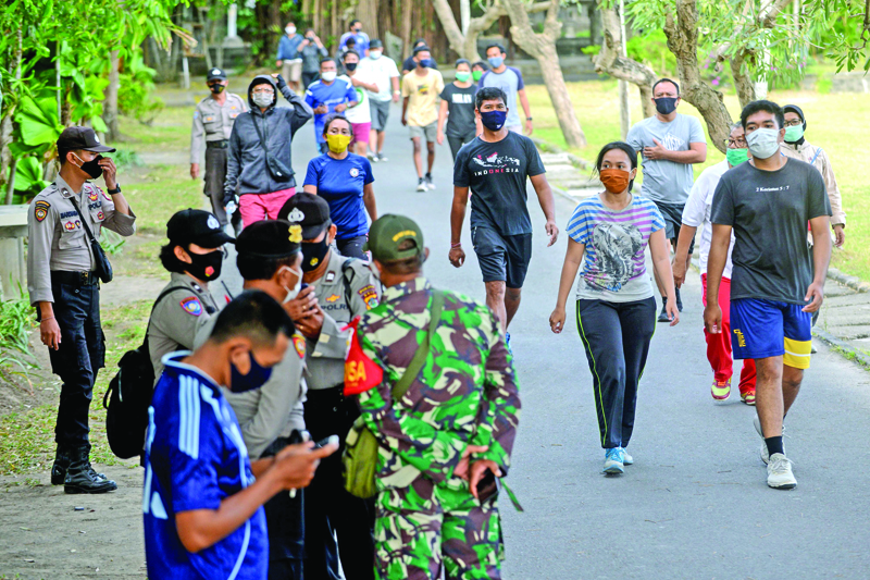 Army and police officers monitor people to ensure they wear face masks as a measure to curb the spread of the COVID-19 coronavirus in Denpasar on Indonesia's resort island of Bali on September 8, 2020. (Photo by SONNY TUMBELAKA / AFP)