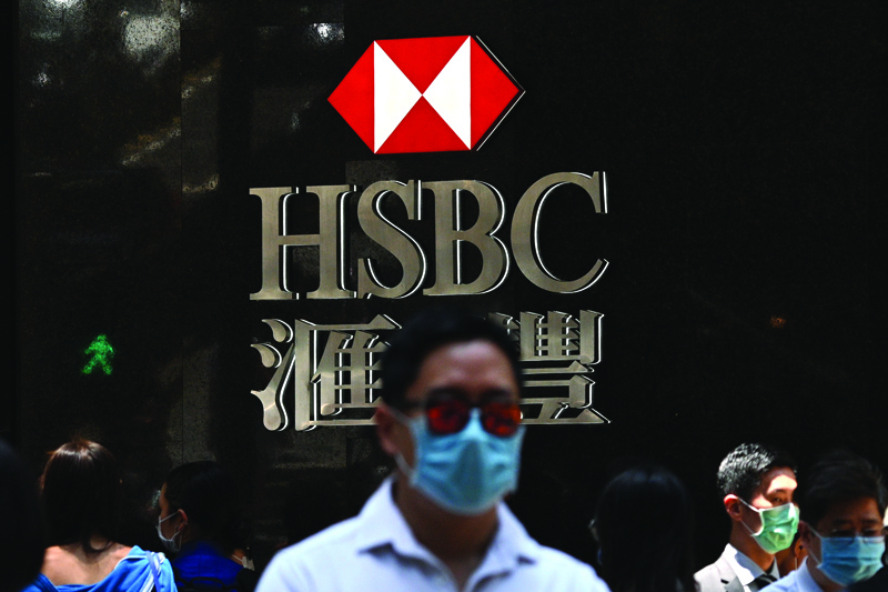 (FILES) In this file photo taken on April 28, 2020, pedestrians wear face masks as they walk past HSBC signage outside a branch of the bank in Hong Kong. - Shares in Hong Kong banking giant HSBC plunged to a 25-year low September 21, 2020 on fears it could be added to a Chinese list of firms deemed a threat to national security and following news it had been accused of allowing fraudulent activity to go unpunished. (Photo by Anthony WALLACE / AFP)