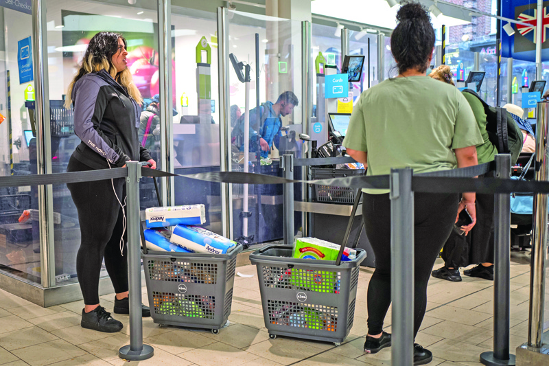 Shoppers queue for self-checkout tills with baskets full of toilet paper at Lidl supermarket in Walthamstow, east London on September 23, 2020. - Britain on Tuesday tightened restrictions to stem a surge of coronavirus cases, ordering pubs to close early and advising people to go back to working from home to prevent a second national lockdown. (Photo by Tolga AKMEN / AFP)