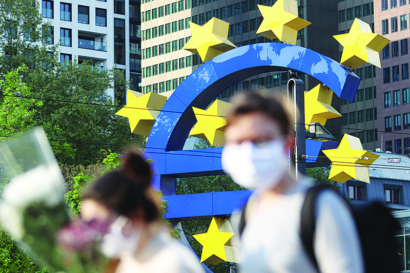(FILES) In this file photo taken on April 24, 2020 people wearing face masks walk in front of a big Euro sign in Frankfurt am Main, western Germany, as the European Central Bank (ECB) headquarter can be seen in the background amid the coronavirus COVID-19 pandemic. - Governors of the ECB Bank are expected on September 10, 2020 to prepare the ground for new stimulus, armed with a new set of forecasts on the bloc's sluggish recovery and with the coronavirus pandemic resurging. (Photo by Yann Schreiber / AFP)
