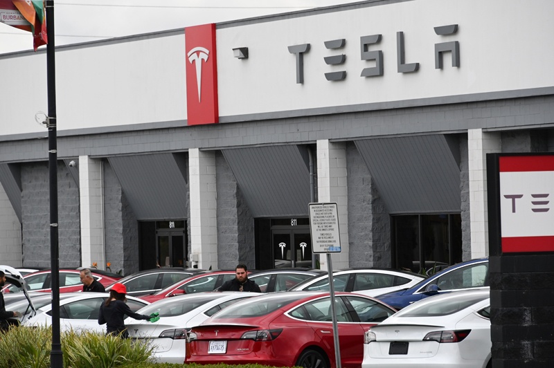 (FILES) In this file photo taken on March 24, 2020 shows Telsa employees work outside a Tesla showroom in Burbank, California. - Tesla on September 22, 2020, said it is slashing battery costs to speed a global shift to renewable energy, and could have a $25,000 model available in three years or so. (Photo by Robyn Beck / AFP)