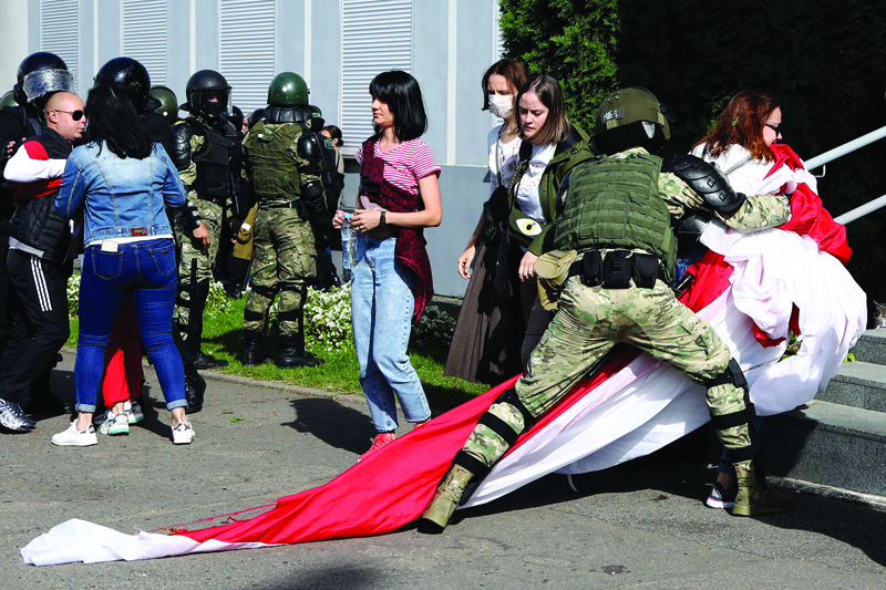 A law enforcement officer detains a woman with a huge former white-red-white flag of Belarus during a rally to protest against the presidential election results in Minsk on September 13, 2020. - Belarusians have been demonstrating against the disputed re-election of President Alexander Lukashenko for a month, with more than 100,000 people flooding the streets of Minsk for four straight weekends. (Photo by - / TUT.BY / AFP)