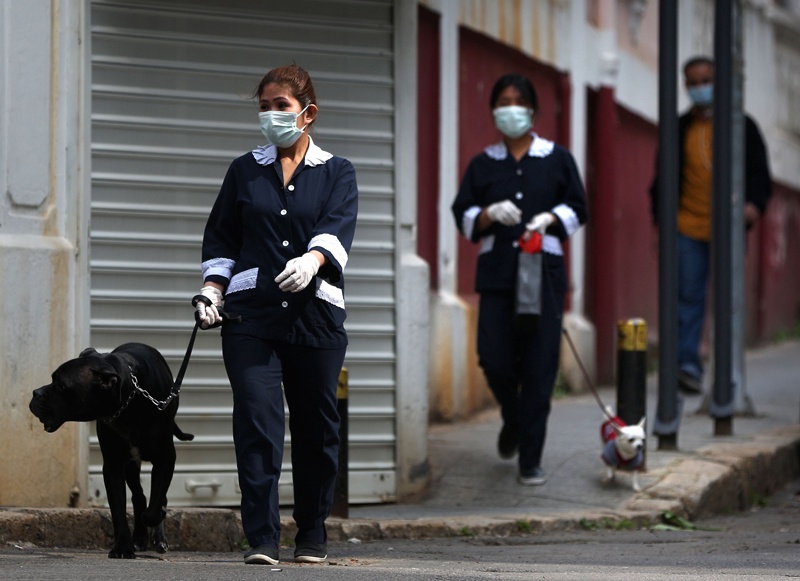 (FILES) A file photo taken on March 26, 2020, shows foreign domestic workers wearing protective face masks walking their employer's dogs in the Lebanese capital Beirut. - Lebanon has approved a new work contract that gives foreign domestic workers the rights to keep their passport and resign, but activists say much more remains to be done to end abuses. After months of consultations, the labour ministry this month published a new and revised work contract for domestic workers, the main legal document governing their stay in the country. (Photo by PATRICK BAZ / AFP)
