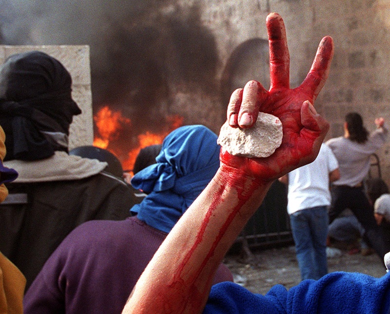 (FILES) In this file photo taken on December 8, 2000, a Palestinian youth holds a stone in his blood-stained hand after carrying a dead fellow protester outside Jerusalem's old city al Aqsa mosque compound, amid clashes which broke out after the second Friday noon prayer of the holy fasting month of Ramadan. - Since a second intifada, or uprising, erupted on September 28, 2000, Palestinians have faced a string of military turnarounds and diplomatic defeats, as well as their own internal divisions. (Photo by AWAD AWAD / AFP)