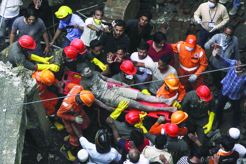 Rescue workers carry a survivor from the rubble of a collapsed three-storey residential building in Bhiwandi on September 21, 2020. - Ten people were killed and up to 25 were feared trapped after a three-storey residential building collapsed before dawn on September 21 in western India, officials said. (Photo by - / AFP)