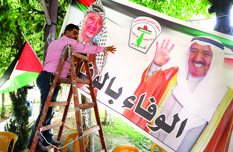Palestinians hang a banner with pictures of the late emir of Kuwait Sheikh Sabah al-Ahmad Al-Sabah (R) and late Palestinian leader Yasser Arafat in the West Bank city of Nablus, on September 30, 2020. - Kuwait today swore in its new emir, Sheikh Nawaf al-Ahmad Al-Sabah, after the death of his half-brother, Sheikh Sabah, who died in the US at the age of 91. (Photo by JAAFAR ASHTIYEH / AFP)