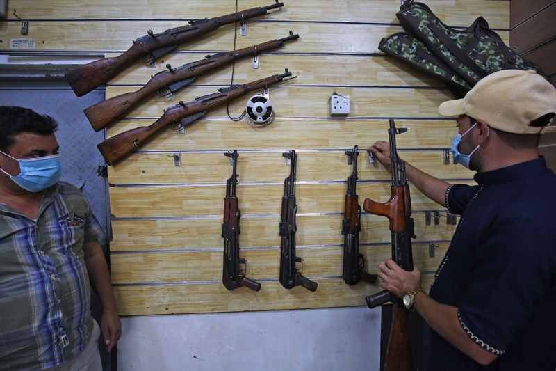 Employees display rifles for sale at a gun shop in the Iraqi capital Baghdad on September 22, 2020. (Photo by AHMAD AL-RUBAYE / AFP)