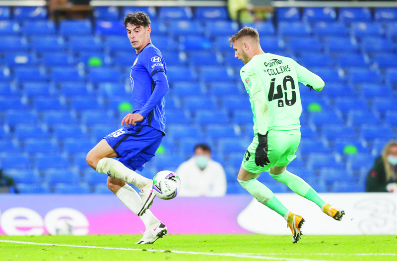 Chelsea's German midfielder Kai Havertz (L) runs past Barnsley's English goalkeeper Brad Collins to score his team's fifth goal  during the English League Cup third round football match between Chelsea and Barnsley at Stamford Bridge in London on September 23, 2020. (Photo by Alastair Grant / various sources / AFP) / RESTRICTED TO EDITORIAL USE. No use with unauthorized audio, video, data, fixture lists, club/league logos or 'live' services. Online in-match use limited to 120 images. An additional 40 images may be used in extra time. No video emulation. Social media in-match use limited to 120 images. An additional 40 images may be used in extra time. No use in betting publications, games or single club/league/player publications. /
