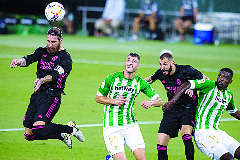 Real Madrid's Spanish defender Sergio Ramos (L) heads the ball next to Real Betis' Argentinian midfielder Guido Rodriguez, French forward Karim Benzema and Portuguese midfielder William Carvalho during the Spanish league football match Real Betis against Real Madrid CF at the Benito Villamarin stadium in Seville on September 26, 2020. (Photo by JORGE GUERRERO / AFP)