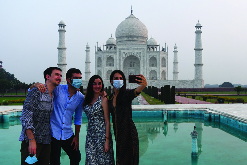 Tourists have their pictures taken at the Taj Mahal in Agra on September 21, 2020. - The Taj Mahal reopened to visitors on September 21 in a symbolic business-as-usual gesture even as India looks set to overtake the US as the global leader in coronavirus infections. (Photo by Sajjad HUSSAIN / AFP)