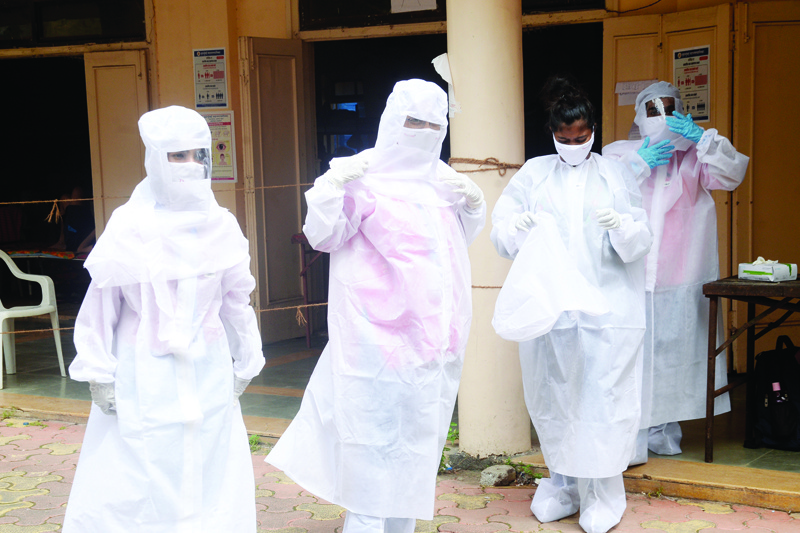 Health workers wear personal protective equipment (PPE) at a Covid-19 Coronavirus testing centre, in Mumbai on September 28, 2020. - India reported its six millionth coronavirus case on September 28 as it surged closer to the United States as the most-infected nation, and authorities pressed ahead with reigniting the economy. (Photo by Indranil MUKHERJEE / AFP)