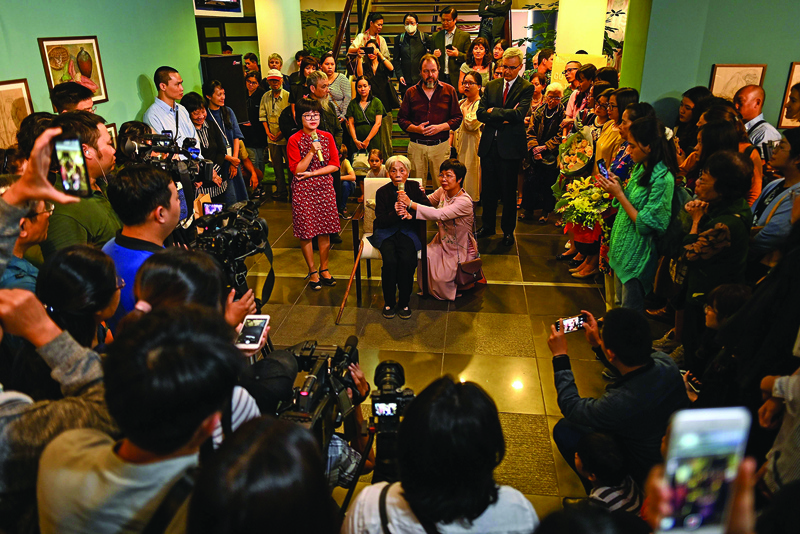 This photograph taken on October 22, 2020 shows 89-year-old Vietnamese artist Mong Bich addressing guests during the opening of her first solo exhibition at the French Cultural Centre in Hanoi. - Bich specialises in silk paintings of daily life and ordinary people, women in particular, and ploughed a lonely furrow during many years of war when artists were steered towards the army or frontline workers as subjects. (Photo by Manan VATSYAYANA / AFP) / To go with Vietnam-art-history, FOCUS by Alice Philipson