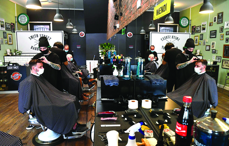 Men have their haircut at a barber shop in Melbourne on October 19, 2020, as some of the city's three-month-old stay-at-home restrictions due to the COVID-19 coronavirus outbreak were further eased on falling infection rates. (Photo by William WEST / AFP)