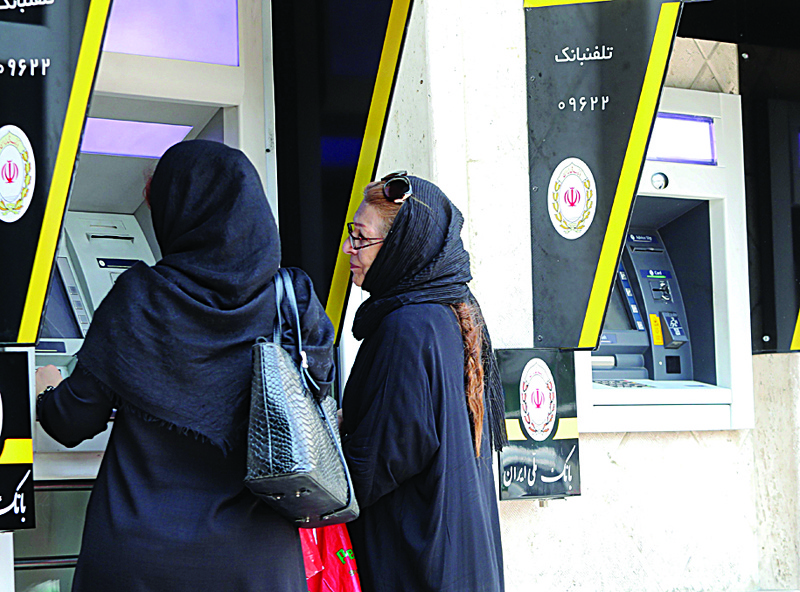 (FILES) In this file photo taken on May 20, 2019, Iranian women use automated teller machines (ATM) in Tehran. - US President Donald Trump's administration on October 8, 2020, imposed sweeping sanctions on Iran's banking sector, taking a major new step aimed at crippling the arch-rival's economy weeks ahead of US elections. (Photo by ATTA KENARE / AFP)