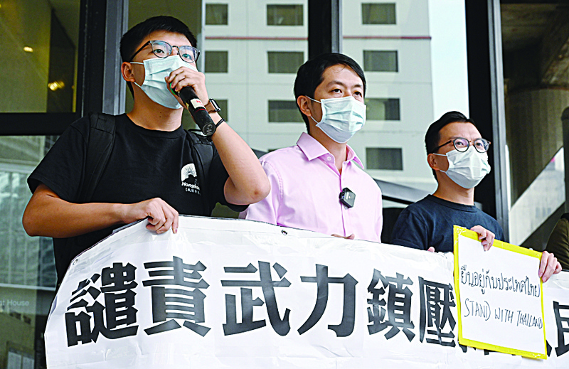 Pro-democracy activist Joshua Wong (L) and lawmaker Ted Hui (2nd L) demonstrate in solidarity with ongoing pro-democracy protests in Thailand, outside the office building where the Thai consulate is located in Hong Kong on October 19, 2020. (Photo by PETER PARKS / AFP)