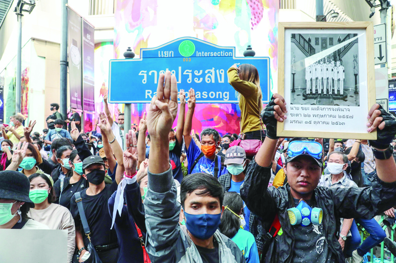 TOPSHOT - Pro-democracy protesters give the three-finger salute as they gather in Bangkok on October 15, 2020, after Thailand issued an emergency decree following an anti-government rally the previous day. (Photo by Jack TAYLOR / AFP)