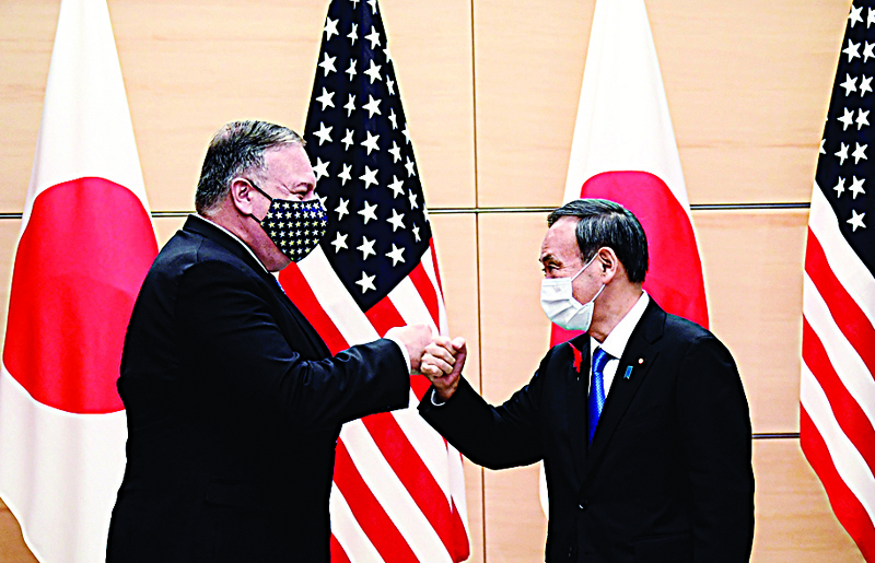 Japan's Prime Minister Yoshihide Suga (R) and US Secretary of State Mike Pompeo (L) bump fists as they meet at the prime minister's office in Tokyo on October 6, 2020, ahead of the four Indo-Pacific nations' foreign ministers meeting. (Photo by CHARLY TRIBALLEAU / POOL / AFP)