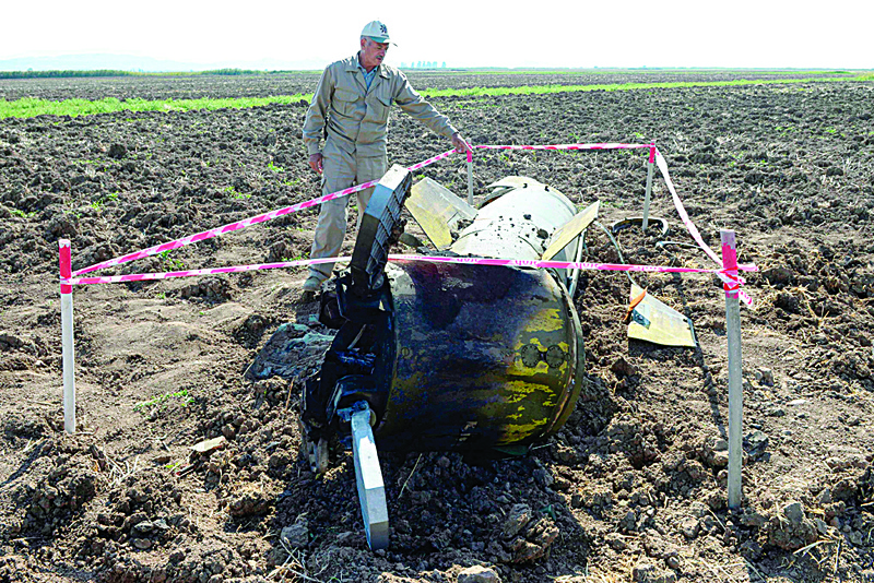 A man stands by what is said is the remains of a Tochka U missile in a field in Fizuli district, Azerbaijan, on October 11, 2020, during the ongoing military conflict between Armenia and Azerbaijan over the breakaway region of Nagorno-Karabakh. (Photo by TOFIK BABAYEV / AFP)