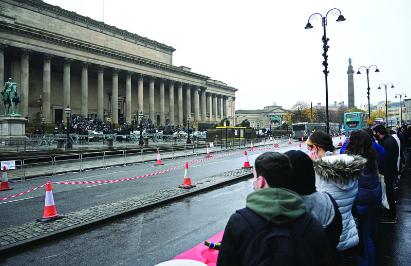 Members of the public, some wearing face masks or coverings due to the COVID-19 pandemic, watch as scenes for a movie are filmed at at George's Hall in Liverpool, north west England on October 12, 2020, as new local lockdown measures are set to be imposed to help stem a second wave of the novel coronavirus COVID-19. - British Prime Minister Boris Johnson is set to present a new three-tiered alert system for coronavirus cases in England on Monday, with Liverpool in the northwest expected to be the only city placed in the top category. Like governments throughout Europe, Johnson's conservative cabinet is seeking to balance bringing down the rate of new infections against concern about the economy and frustration among voters. (Photo by Paul ELLIS / AFP)