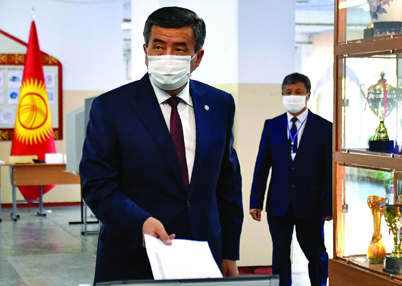 Kyrgyz President Sooronbay Jeenbekov wearing a face mask casts his ballot at a polling station during parliamentary election in Bishkek on October 4, 2020, amid the ongoing coronavirus pandemic. (Photo by Vladimir VORONIN / POOL / AFP)