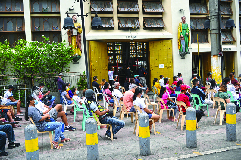 In this picture taken on October 9, 2020, Catholic faithful sit outside the Quiapo church in Manila, as health protocols imposed by authorities limit church goers inside the church to filling only 10 percent of their seating capacity. - After months of livestreaming mass to millions of faithful from behind closed doors, churches in the Catholic-majority Philippines are beginning to reopen. (Photo by Ted ALJIBE / AFP) / TO GO WITH: Philippines-Religion-Health-Virus, by Ron LOPEZ