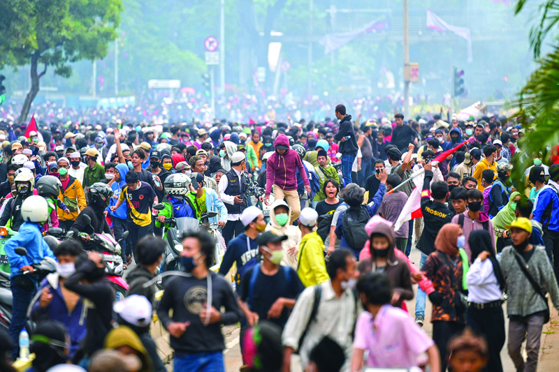 Protesters disperse after police fired tear gas at a rally against a controversial new law passed last week which critics fear will favour investors at the expense of labour rights and the environment, in Jakarta on October 13, 2020. (Photo by BAY ISMOYO / AFP)