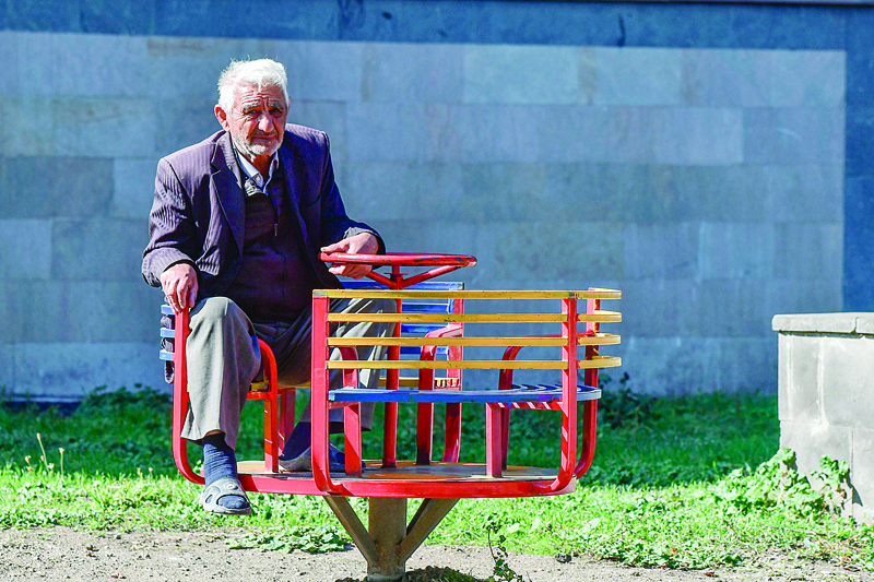 An elderly man sits at a playground in front of an apartment building in the city of Stepanakert on October 12, 2020, during the ongoing military conflict between Armenia and Azerbaijan over the breakaway region of Nagorno-Karabakh. (Photo by ARIS MESSINIS / AFP)