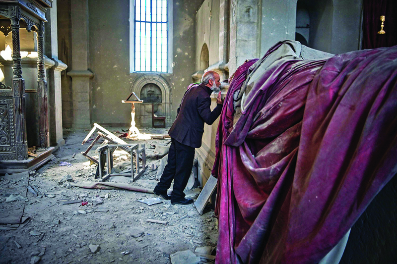 Arthur Sahakyan, 63, prays inside the damaged Ghazanchetsots (Holy Saviour) Cathedral in the historic city of Shusha, some 15 kilometers from the disputed Nagorno-Karabakh province's capital Stepanakert, that was hit by a bomb during the fighting between Armenia and Azerbaijan over the breakaway region, on October 13, 2020. - Nagorno-Karabakh broke away from Azerbaijan in a 1990s war that claimed the lives of some 30,000 people. The Armenian separatists declared independence, but no countries recognise its autonomy and it is still acknowledged by world leaders as part of Azerbaijan. (Photo by ARIS MESSINIS / AFP)