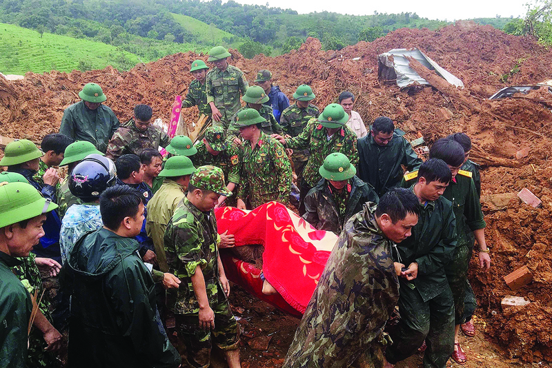 TOPSHOT - This picture taken on October 18, 2020 and released by the Vietnam News Agency on October 18, 2020 shows military personnel carrying a body recovered from the site of a landslide in central Vietnam's Quang Tri province. (Photo by STR / Vietnam News Agency / AFP)