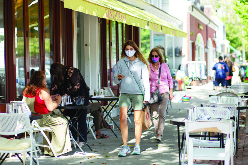 People wearing face masks walk by Main Street on September 30, 2020 in Southampton, New York. - Beach umbrellas are in back garages as temperatures cool, but wealthy New Yorkers are staying in the Hamptons beyond summer, fearful of the pandemic and rising crime in the city. (Photo by Kena Betancur / AFP)