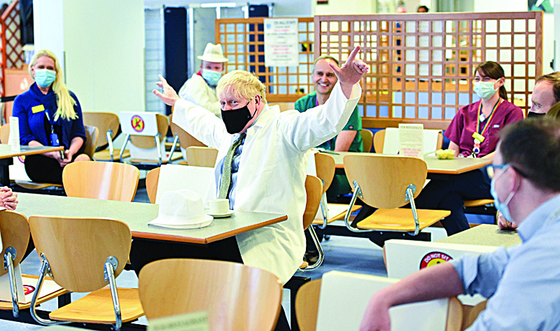 Britain's Prime Minister Boris Johnson, wearing a face mask or covering due to the COVID-19 pandemic, reacts as he sits with hospital workers during his visit to Royal Berkshire NHS Hospital in Reading, west of London on October 26, 2020, to mark the publication of a new review into hospital food. (Photo by Jeremy Selwyn / POOL / AFP)
