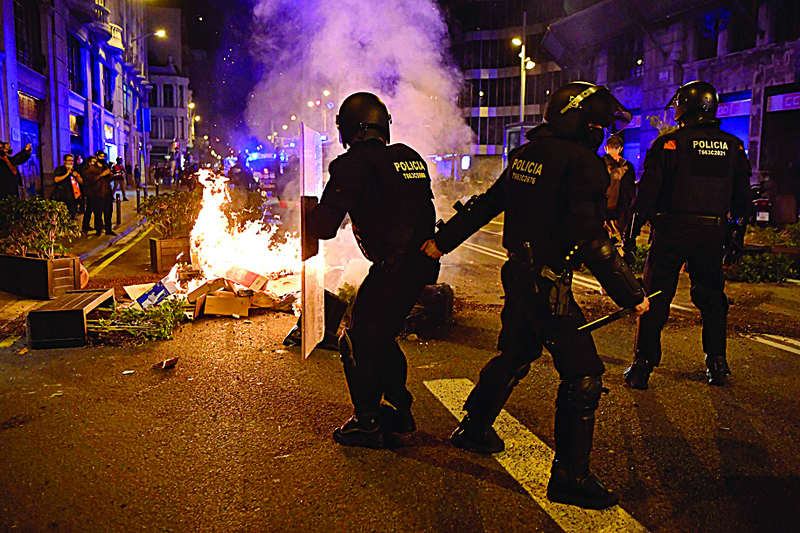 Members of the Catalan regional police force Mossos d'Esquadra take position next to burning trash set on fire by protesters during a demonstration against new coronavirus restrictions in Barcelona on October 30, 2020. - One by one, Spain's regions have announced regional border closures in the hope of avoiding a new lockdown like in France. The central government unveiled a state of emergency to give regional authorities the tools to impose curfews and close their borders to anyone moving without just cause. (Photo by Pau BARRENA / AFP)