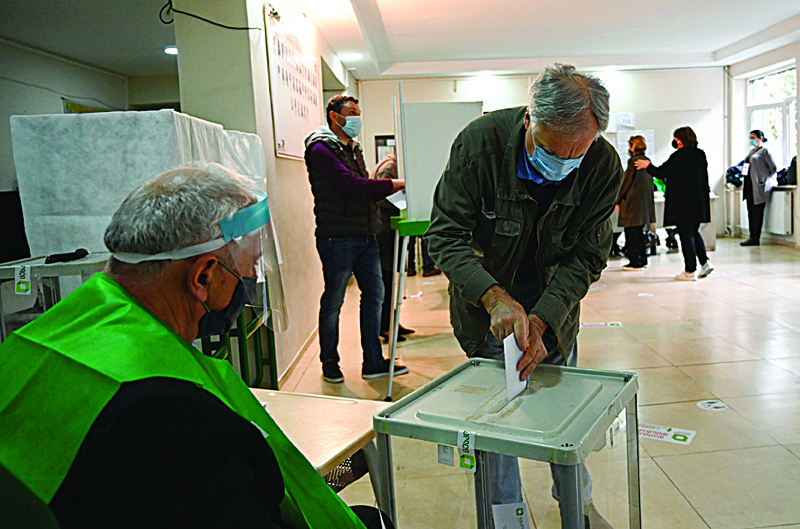 A man casts his ballot at a polling station during Georgia's parliamentary election in Tbilisi on October 31, 2020, amid the ongoing coronavirus disease pandemic. (Photo by Vano SHLAMOV / AFP)
