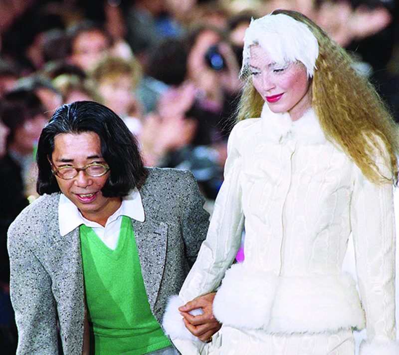 A picture taken on March 18, 1995, in Paris shows Paris-based Japanese designer Kenzo (L) posing with a model at the end of his Fall-Winter 1995-96 ready-to-wear collection show. - Japan's most famous fashion designer Kenzo Takada, founder of the global Kenzo brand, died in the French capital on October 4, 2020 aged 81 after contracting coronavirus. (Photo by Gerard JULIEN / AFP)