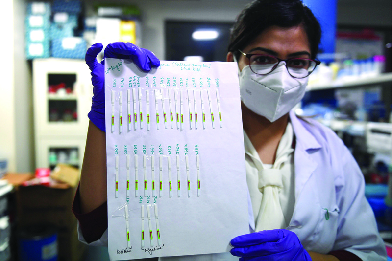 (FILES) In this file photo taken on October 7, 2020, a researcher holds a sheet with paper strip samples for Covid-19 coronavirus tests developed by the CSIR-Institute of Genomics and Integrative Biology (IGIB) which could give results at a similar speed of pregnancy tests, at a laboratory of the IGIB in New Delhi. - A fast and cheap paper-based coronavirus test will soon be available across India, with scientists hopeful it will help turn the tide on the pandemic in one of the world's worst-hit nations. (Photo by Money SHARMA / AFP)