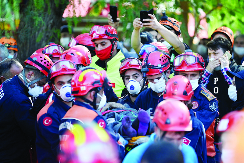 Search and rescue teams carry a victim on a stretcher after pulling her out of the rubble of a collapsed building on October 31, 2020, in Izmir, after a powerful earthquake struck Turkey's western coast and parts of Greece. - A powerful earthquake hit Turkey and Greece on October 30, killing at least 26 people, levelling buildings and creating a sea surge that flooded streets near the Turkish resort city of Izmir. (Photo by OZAN KOSE / AFP)