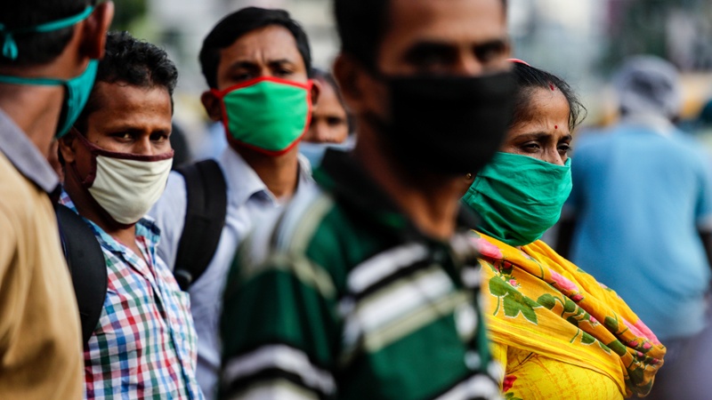 Commuters wearing face masks as a precautionary measure against the coronavirus wait for a bus in Kolkata, India, Saturday, Oct. 10, 2020. India's total coronavirus positive cases near 7 million with another 73,272 infections reported in the past 24 hours. The Health Ministry on Saturday put the total positive caseload at 6.97 million, second to 7.66 million infections registered in the worst-hit United States. (AP Photo/Bikas Das)