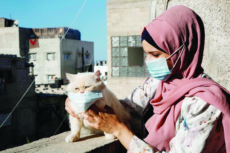 Palestinian artist Khulud al-Desouki pets a cat during lockdown at home in Khan Yunis in the southern Gaza Strip, on October 12, 2020, amid strict restrictions due to the COVID-19 pandemic. (Photo by MOHAMMED ABED / AFP)