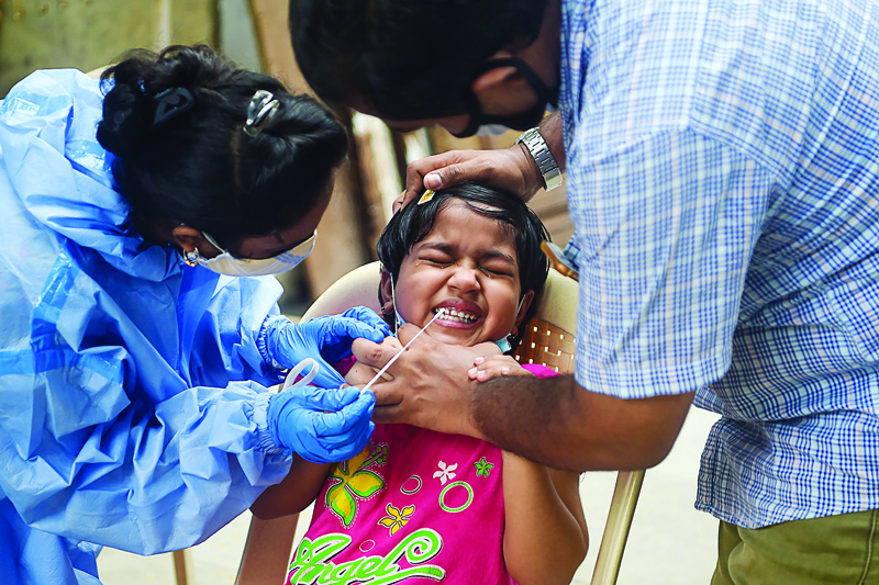 A health worker collects a swab sample from a child during a medical screening for the Covid-19 Coronavirus, in Mumbai on October 3, 2020. - Deaths from the novel coronavirus in India passed 100,000 on October 3, official data showed as the pandemic continued to rage across the world's second most populous country. (Photo by Punit PARANJPE / AFP)