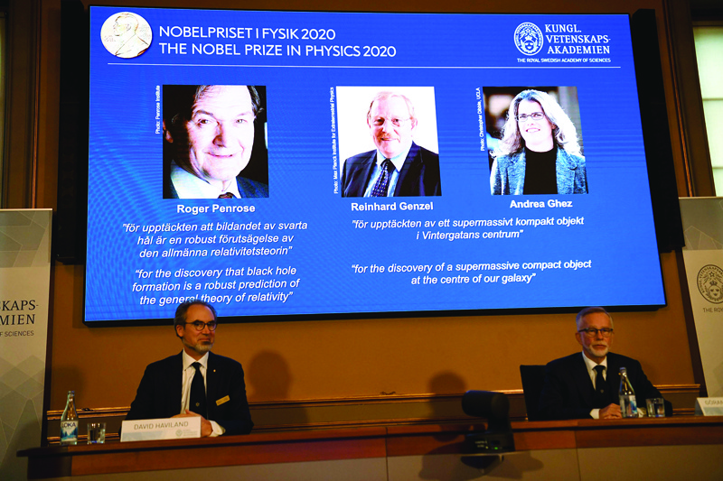 David Haviland (L), member of the Nobel Committee for Physics, and Goran K Hansson, Secretary General of the Academy of Sciences, (L-R) sit in front of a screen displaying the winners of the 2020 Nobel Prize in Physics (L-R) Briton Roger Penrose, Reinhard Genzel of Germany  and Andrea Ghez of the US, during a press conference at the Royal Swedish Academy of Sciences, in Stockholm, on October 6, 2020. - Roger Penrose of Britain, Reinhard Genzel of Germany and Andrea Ghez of the US won the Nobel Physics Prize on Tuesday for their research into black holes, the Nobel jury said. (Photo by Fredrik SANDBERG / TT NEWS AGENCY / AFP) / Sweden OUT
