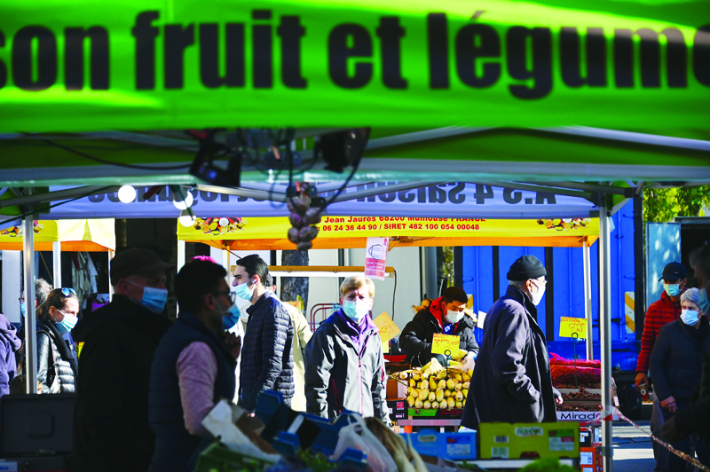Shoppers buy food at an open market in Mulhouse on October 31, 2020, on the second day of a new national lockdown in France aimed at curbing the spread of the Covid-19 pandemic, caused by the novel coronavirus. (Photo by SEBASTIEN BOZON / AFP)