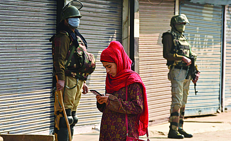 A resident walks past Indian army soldiers standing guard next to closed shops during a one-day strike called by the All Parties Hurriyat Conference (APHC) against Against Indian government decision to open Kashmir land for all Indians, in Srinagar on October 31, 2020. (Photo by TAUSEEF MUSTAFA / AFP)