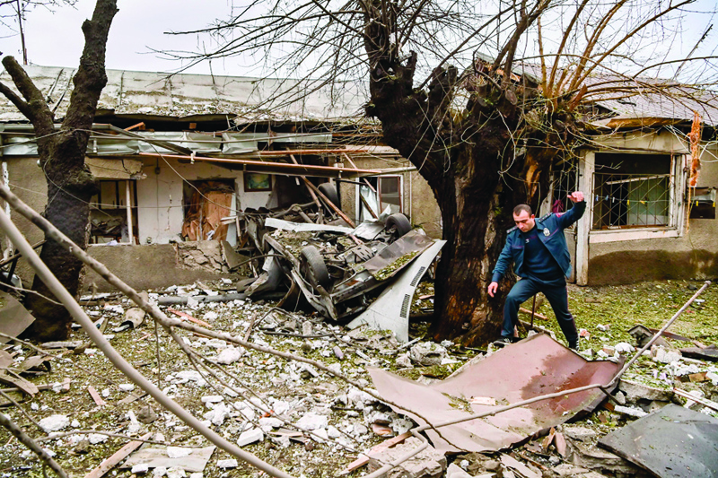 TOPSHOT - A police officer steps over debris in the yard of a destroyed house after shelling in the breakaway Nagorno-Karabakh region's main city of Stepanakert on October 7, 2020, during the ongoing fighting between Armenia and Azerbaijan over the disputed region. (Photo by ARIS MESSINIS / AFP)
