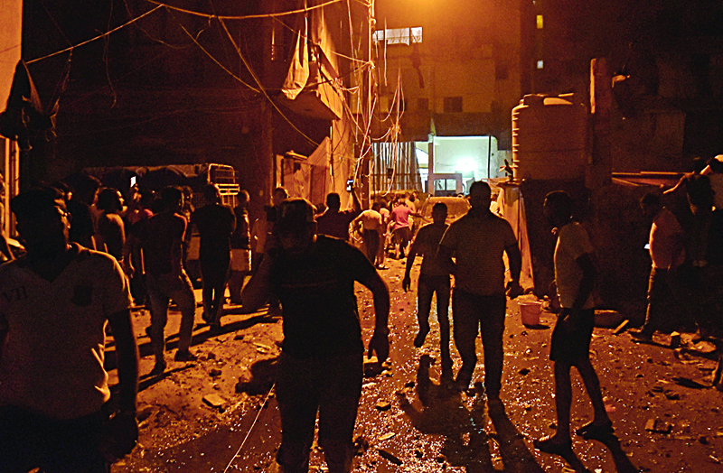 People gather at the site of a fuel tank explosion in Beirut's Tariq al-Jdide neighbourhood on October 9, 2020. - An explosion and a fuel tank fire in the Lebanese capital killed four people, rescuers said as panic spread in a city already ravaged by a monster blast in August. (Photo by - / AFP)