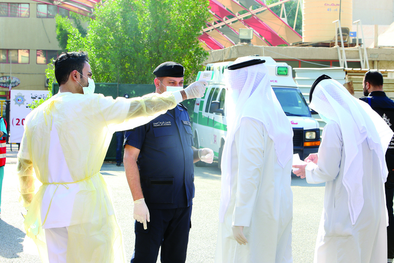 A health official checks the body temperature of a Kuwaiti candidates upon their arrival at the Department of Elections, on the first day of candidate's registrationon, on October 26, 2020 in Kuwait City to register for the upcoming parliamentary election.