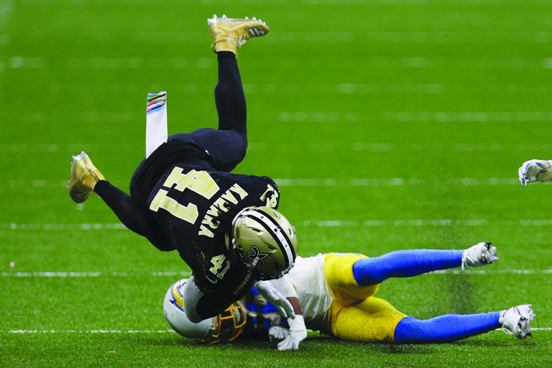 NEW ORLEANS, LOUISIANA - OCTOBER 12: Alvin Kamara #41 of the New Orleans Saints is tripped by Casey Hayward #26 of the Los Angeles Chargers during their NFL game at Mercedes-Benz Superdome on October 12, 2020 in New Orleans, Louisiana.   Chris Graythen/Getty Images/AFP