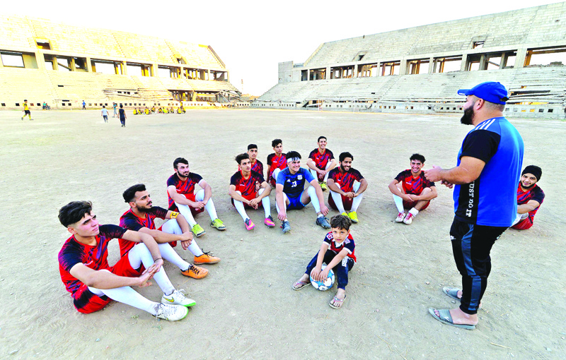 Mohamed Fathi (R), coach of Al-Mosul FC, speaks with his team players at the ravaged al-Idara al-Mahalia stadium, which was once used by Islamic State group fighters as a weapons depot, near the northern Iraqi city of Mosul on October 22, 2020. - Jihadi fighters from the Islamic State (IS) group seized Mosul in 2014, later expanding its so-called 'caliphate' to over a third of Iraq and into neighbouring Syria. In 2017, Iraqi and coalition forces forced the hardened insurgents out in a grinding urban battle that left the ancient city in ruins. The bullet-riddled 20,000-seater stadium, home to Mosul Sports Cub, was not spared -- the extremist fighters used the pitch as a firing ground for rockets. (Photo by Zaid AL-OBEIDI / AFP)
