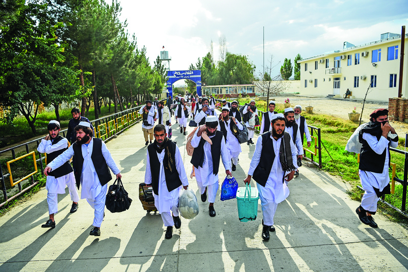 (FILES) In this file photo taken on July 31, 2020 Taliban prisoners walk with their belongings as they are in the process of being potentially released from Pul-e-Charkhi prison, on the outskirts of Kabul. - Almost two decades after the United States launched what would become its longest-ever war with air strikes on Afghanistan's ruling Taliban regime, the hardline group are in a stronger position than ever. The invasion on October 7, 2001 quickly toppled the militants, who had harboured Al-Qaeda, the group behind the September 11 attacks that killed nearly 3,000 people in America just weeks earlier. (Photo by WAKIL KOHSAR / AFP)